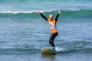 Smiling man riding a wave during a beginner surf lesson in Ericeira, part of the Moka Surf House Surf School Package.