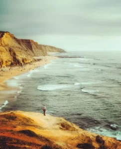 Aerial view of Ericeira coastline with dramatic cliffs, ocean waves and winding coastal road—perfect location for yoga and surf retreats.