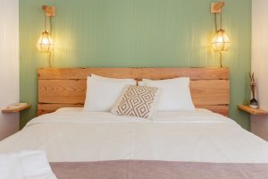 Front view of the bed with hanging lamps and wooden headboard in the First Floor Double Room at Moka Surf House.
