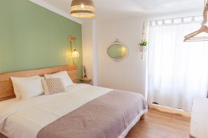 Bright and cozy First Floor Double Room at Moka Surf House, featuring natural light, green accent wall, and minimalist boho decor.