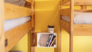 Detail of a shared room with wooden bunk beds, books, and a small plant at Moka Surf House & Yoga Retreat in Portugal.
