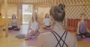 Yoga students in a seated meditation session inside a bright wooden yurt at Moka Surf House, part of the Yoga Package experience.