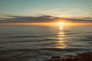 Tranquil sunset over the Atlantic Ocean with golden light reflecting on the water, representing the peaceful ambiance of coastal Ericeira.