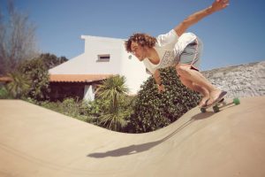 Man practicing surf movements on a Carver skateboard in a wave ramp, in a sunny garden in Ericeira.