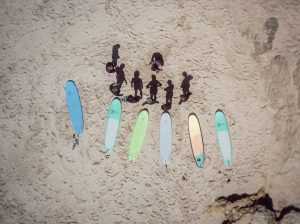 Aerial view of a group surf lesson on the beach in Ericeira with colorful softboards arranged in the sand, part of Moka Surf House experience.