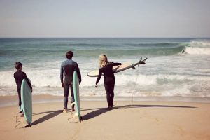 Three surfers standing on the shore, ready to enter the ocean with boards in hand during a private surf lesson in Ericeira.